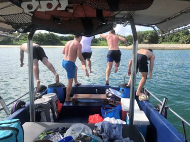 Friends jumping off a boat